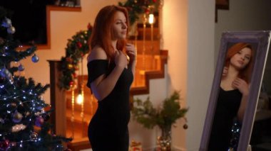 Noel için dekore edilmiş misafirleri karşılamadan önce son hazırlıklar. Genç bir kadın aynaya bakarken kızıl saçlarını düzeltiyor.