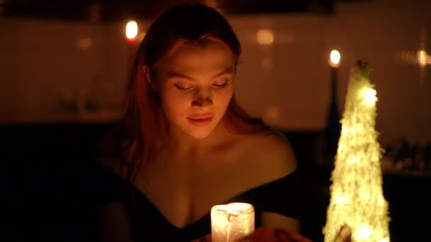 在一个点着蜡烛的黑暗的房间里 一个年轻貌美的女人在想了想什么以后 吹灭了蜡烛 看着相机笑了 — 图库视频影像