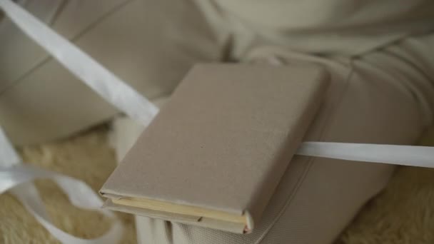 Жінка Сидить Підлозі Прикрашає Подарунок Зав Язавши Його Білою Стрічкою — стокове відео