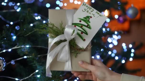 Zbliżenie Handmade Prezent Noworoczny Tle Drzewa Lampkami Świątecznymi — Wideo stockowe