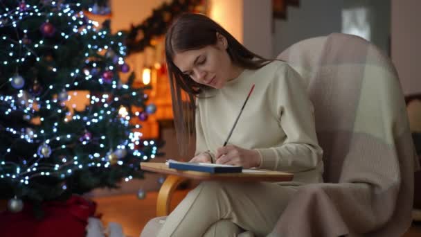 Einem Schaukelstuhl Neben Einem Weihnachtsbaum Sitzend Konzentriert Sich Eine Frau — Stockvideo