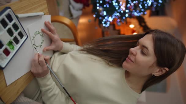 Вертикальне Відео Жінка Малює Зелений Акварельний Різдвяний Вінок Листівці Сидячи — стокове відео