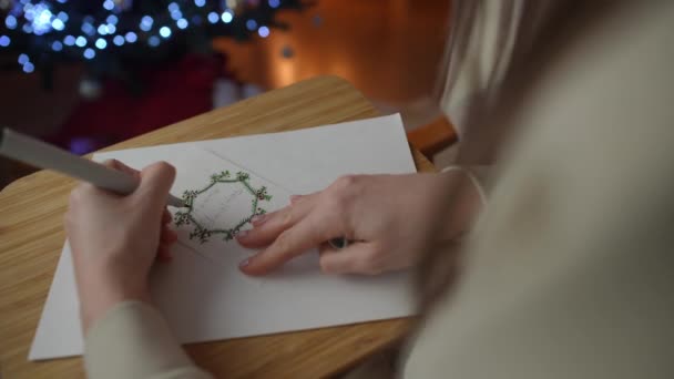 Een Linkshandige Vrouw Tekent Een Handgemaakte Kerstkaart Terwijl Een Stoel — Stockvideo