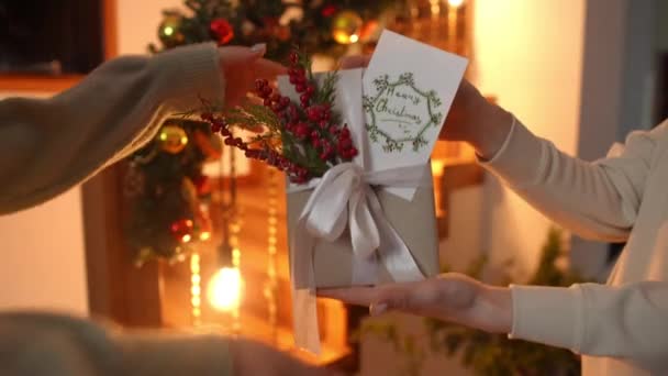 一位女士送给她的朋友一份圣诞礼物 礼物是她亲手制作的 背景是为圣诞节装饰的楼梯 — 图库视频影像