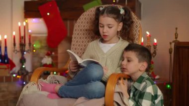 Çocuklar Noel arifesinde boş zamanlarını şöminenin yanında oturarak geçirirler. Bir kız sallanan sandalyede otururken kitap okur ve bir oğlan onu dikkatle dinler.