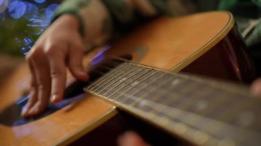 Gitarın tepesine yakın çekim, telleri koparan bir erkek eli.