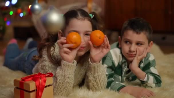 Dívka Chlapec Ležící Koberci Vánočního Stromečku Baví Hraním Mandarinkami — Stock video