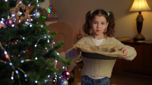 그녀의 베이킹 시트와 크리스마스 근처에 서있는 소녀는 카메라에 유리에 신선하게 — 비디오