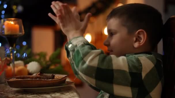 Мальчик Сидящий Столом Украшенным Рождество Пытается Наблюдать Рождественский Ритуал — стоковое видео