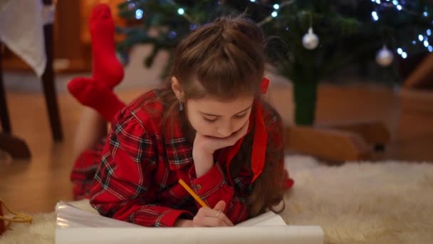 Świąteczny Wypoczynek Domu Przy Choince Dziewczyna Leży Dywanie Rysuje — Wideo stockowe