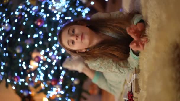 Вертикальне Відео Різдвяний Відпочинок Будинку Біля Ялинки Дівчина Лежить Килимі — стокове відео