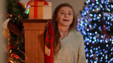 Noel için ev tatili. Bir kız oynuyor ve evin merdivenlerinde Noel ağacının arka planına karşı eğleniyor.