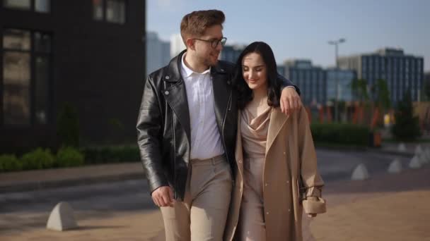 スローモーション 若くてスタイリッシュでハッピーなカップルは 現代的な住宅複合体の背景に歩いています — ストック動画
