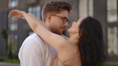 Ağır çekim. Yakın plan. Güzel bir çift dramatik bir şekilde modern bir binanın arka planına sarılıyor. Bir erkek bir kadını nazikçe boynundan öper.