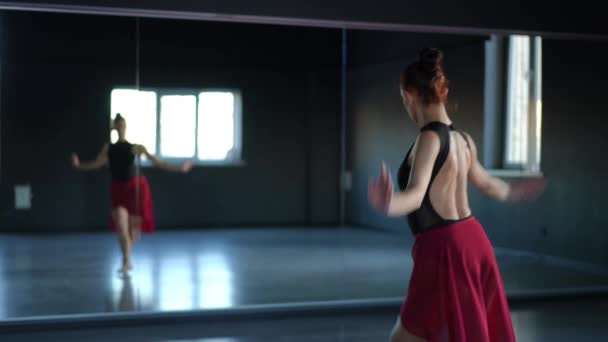 一个芭蕾舞演员在舞厅里练习 一个漂亮的女人完善了她的动作 在舞厅的镜子里看着她的倒影 — 图库视频影像