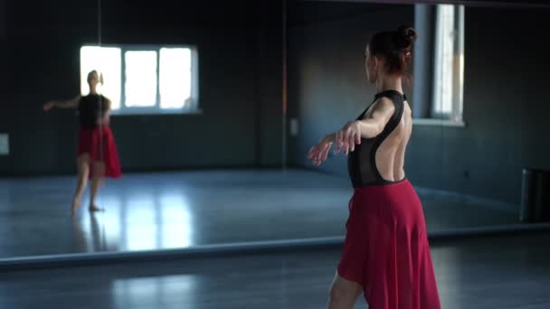 一位美丽而优雅的芭蕾舞演员表演着流畅的动作 并在舞厅的镜子中看着自己的倒影 — 图库视频影像