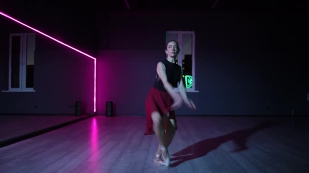 一位美丽的芭蕾舞演员带着霓虹灯照明的镜子在黑暗的舞蹈大厅里跳舞 舞女优美的芭蕾舞动作 — 图库视频影像
