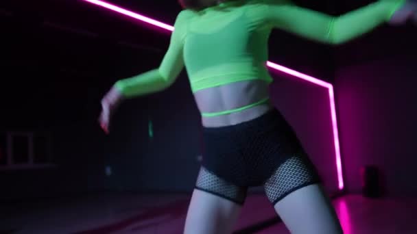 现场摄像头 在黑暗的舞厅里 一个穿着亮丽舞服的女孩带着霓虹灯跳舞 — 图库视频影像