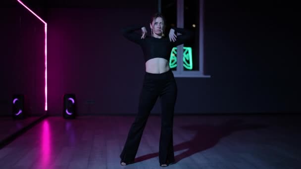 ライブカメラ ネオン照明付きの暗い振り付けホールでプロのダンス女性 動きを実行するときにアクティブな腕スイングとジェスチャー — ストック動画