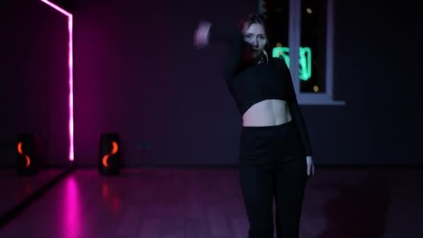 ライブカメラ ネオン照明で振付ホールで踊る女性 ダンスをしながら腕やジェスチャーを積極的に振る舞う — ストック動画