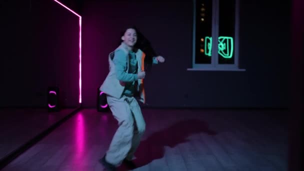 ライブカメラ エネルギッシュなヒップホップを踊る陽気な少女 ネオン照らされた鏡で暗い振付ホール — ストック動画
