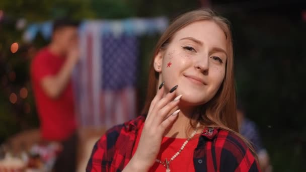 女孩的近照 脸颊上挂着一颗星星 独立日 7月4日 一个女孩在外面和一群朋友在一起 — 图库视频影像