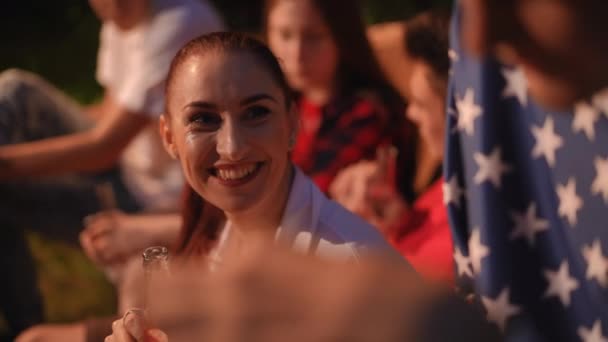クローズアップ 屋外パーティーの友人の会社で笑顔の女性 女性は笑顔 ガラス瓶から水を飲む — ストック動画