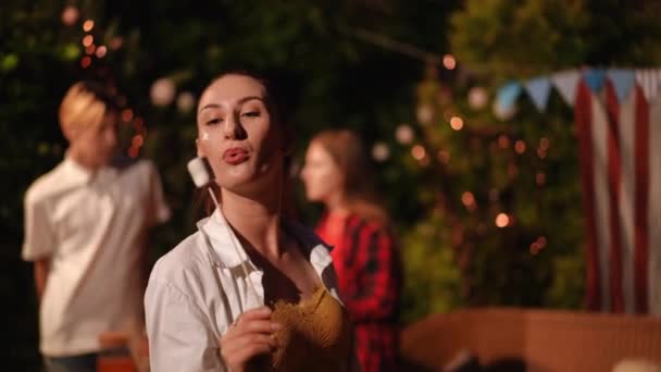 在与朋友举行的户外派对上 一个女孩和一个拿着烤棉花糖棒的男人表现出了彼此的爱意 — 图库视频影像