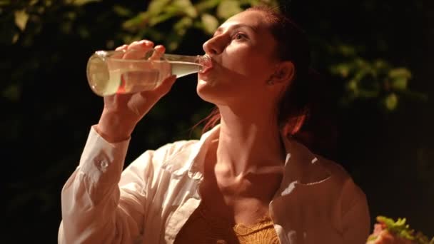 Κοντινό Πλάνο Κορίτσι Πίνει Από Ένα Γυάλινο Μπουκάλι Και Τρώει — Αρχείο Βίντεο