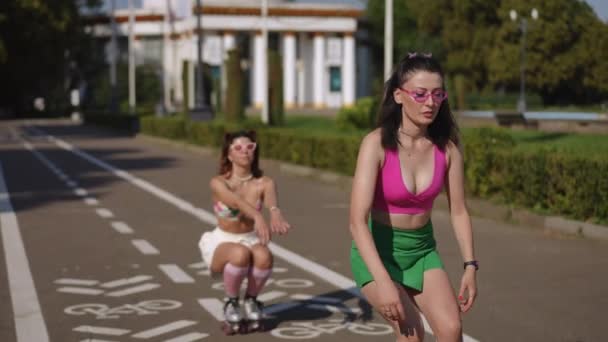 Duas Meninas Óculos Sol Patins Movem Sincronicamente Através Parque Cidade — Vídeo de Stock