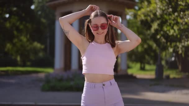 Ein Mädchen Mit Sonnenbrille Lächelt Richtet Ihre Zöpfe Auf Den — Stockvideo
