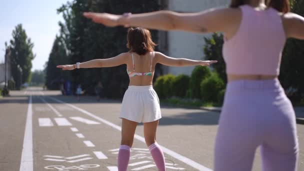 Dwie Dziewczyny Wrotkach Zwolnionym Tempie Tańczą Synchronicznie Miejskim Parku Słoneczny — Wideo stockowe