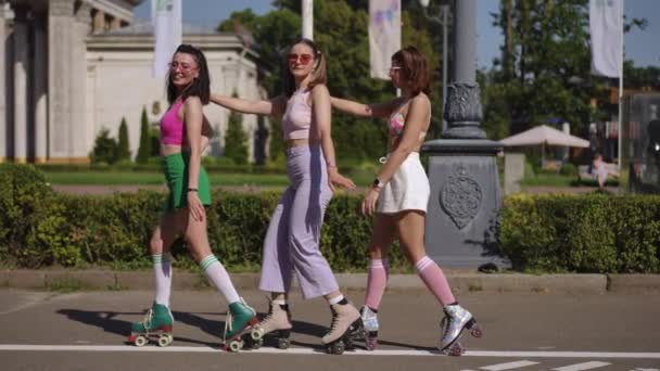 ライブカメラ ローラースケートの3人の若い女性は 暑い晴れた日に市の公園でゆっくりとした動きでムーンウォークを行います — ストック動画