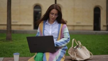 Gözlüklü güzel bir kadın, dizüstü bilgisayarında yazmayı bitirmiş, onu kapatıyor ve kafasını geriye doğru atıyor, rahatça iç çekiyor. Dışarıda dizüstü bilgisayarla çalışmak..