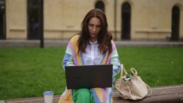 Kobieta Pracuje Laptopie Siedzi Ławce Parku Miejskim Pije Kawę Papierowej — Wideo stockowe