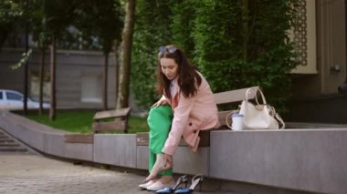 İş kadını toplantıdan önce şık ayakkabılar giyer, yazın şehir parkında bir bankta oturur.