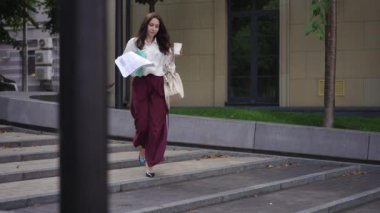 Bir kadın sokakta merdivenlerden inerken elindeki kağıtları ve bir bardak kahveyi düşürdü. Yavaş çekim