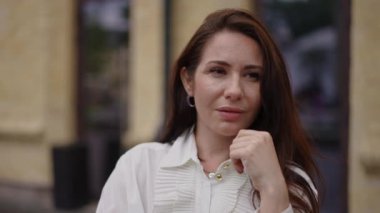 Şehir manzarasına karşı uzun saçlı şık bir iş kadınının portresi. Kadın gülümsüyor ve kameraya bakıyor. Yakın plan..