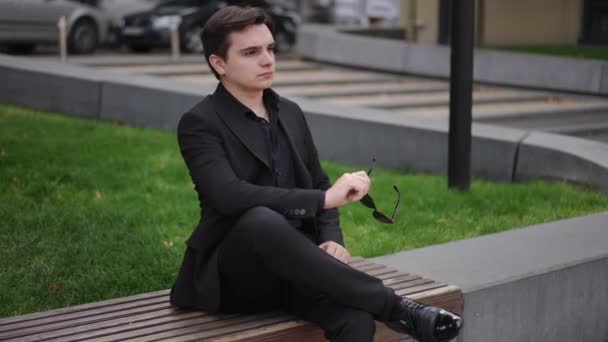 Młody Biznesmen Garniturze Siedzący Ławce Parku Miejskim Mężczyzna Siedzi Skrzyżowanymi — Wideo stockowe