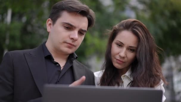 一个男人坐在公园外面 用笔记本电脑向一个女人展示他的作品 后续行动 — 图库视频影像