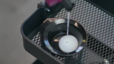 Şişeden beyaz, jel gibi, opak bir sıvı küçük siyah, yuvarlak, plastik bir kabın içine dökülüyor. Yakın plan.