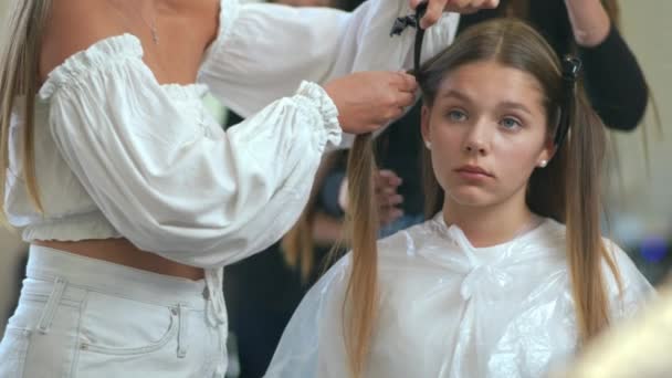 慢动作特写 女理发师把头发在女孩的头上分成几股 用发夹把它们粘在一起 — 图库视频影像