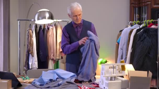 Stylish Elderly Man Looks Shirts Scattered Table Man Takes Shirts — Stock Video