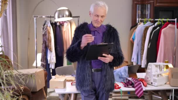 Stylischer Extravaganter Älterer Männlicher Modedesigner Hält Ein Tablet Mit Papieren — Stockvideo