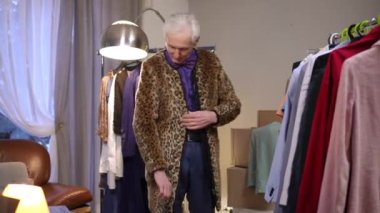 Müsrif yaşlı bir erkek moda tasarımcısı modern bir evin soyunma odasında şık bir leopar desenli ceket deniyor.