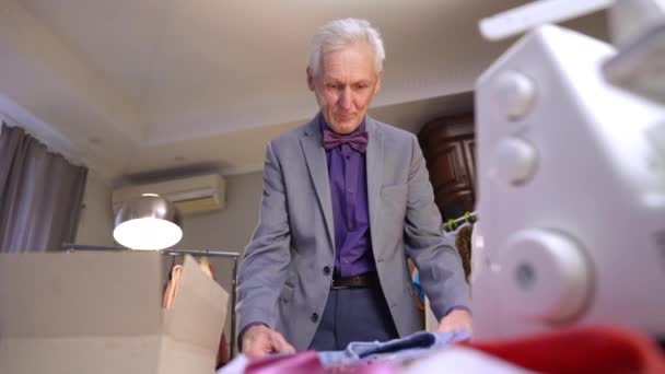 Ein Älterer Grauhaariger Modeschöpfer Packt Vorsichtig Ein Blaues Hemd Einen — Stockvideo