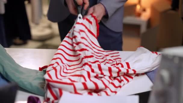一个怒气冲冲的男人用剪刀剪开红色条纹的白衣 紧张地把它们扔在桌上 — 图库视频影像