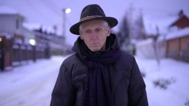 Вечером Заснеженной Улице Зажженными Фонарями Идет Мрачный Пожилой Человек Шляпе — стоковое видео