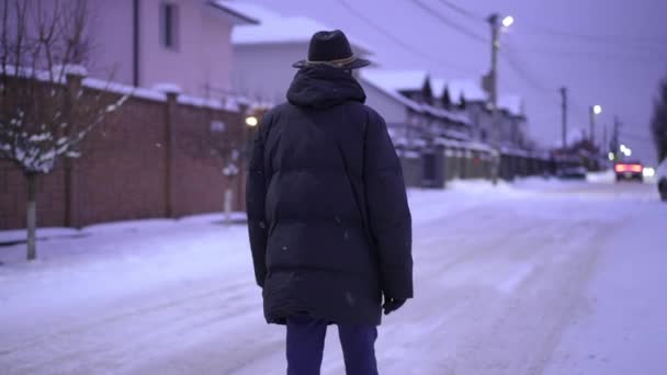 后视镜傍晚时分 一位头戴帽檐的老人 头戴灯笼 沿着雪地的街道走着 — 图库视频影像