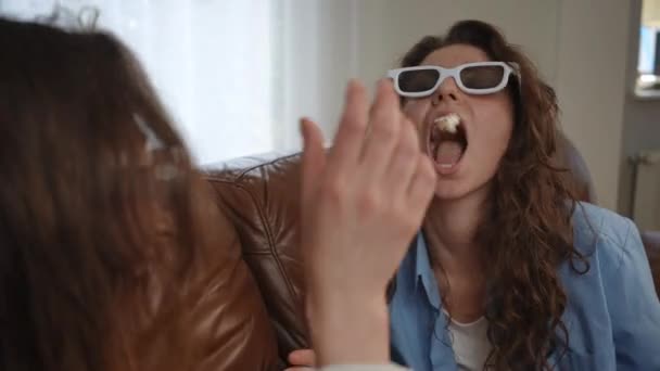 Két Fehér Szemüveges Lány Kanapén Nevetnek Popcornt Dobálnak Amit Szájukba — Stock videók